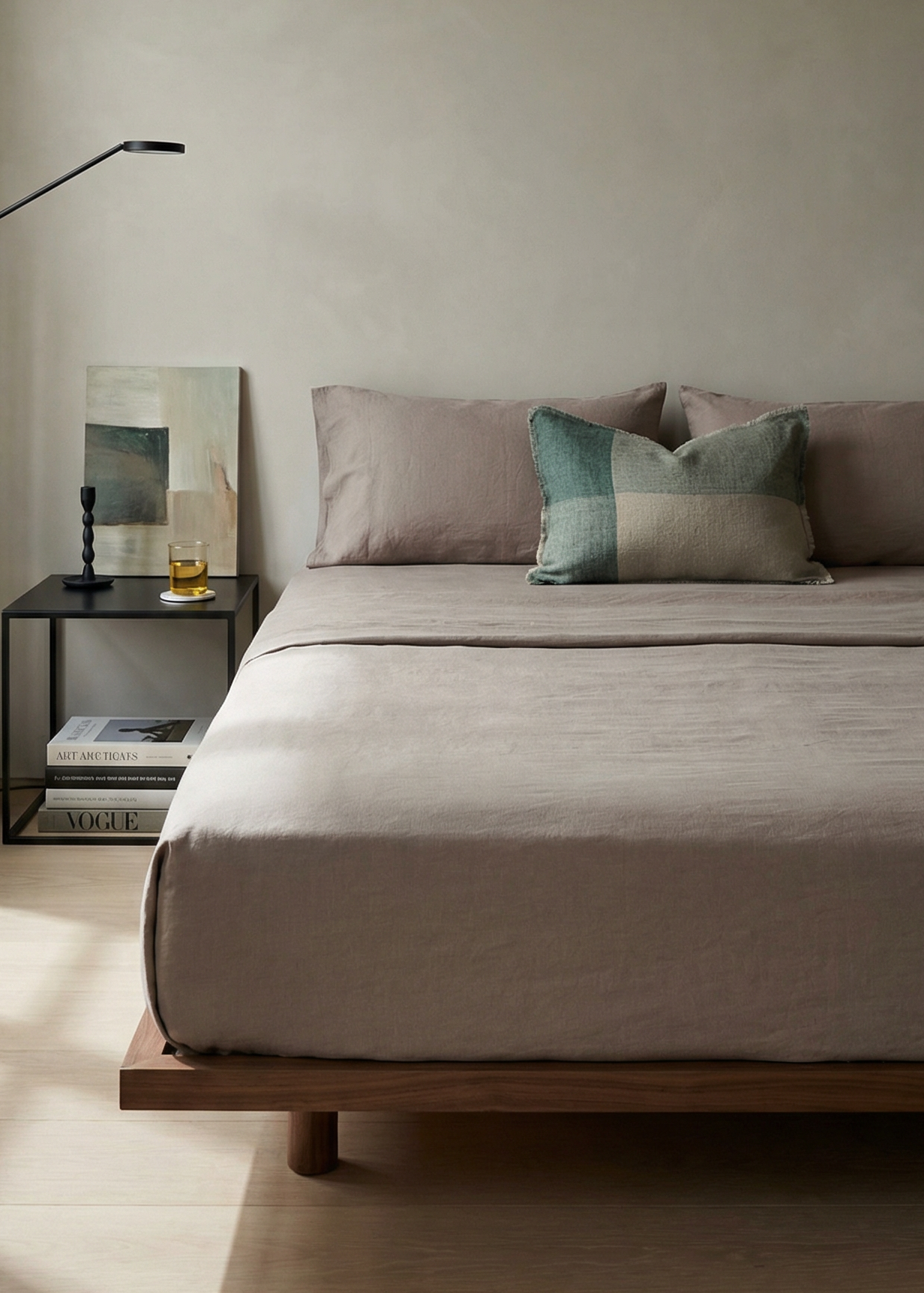 Minimalist bedroom with a bed, side table, and lamp in a neutral color scheme.