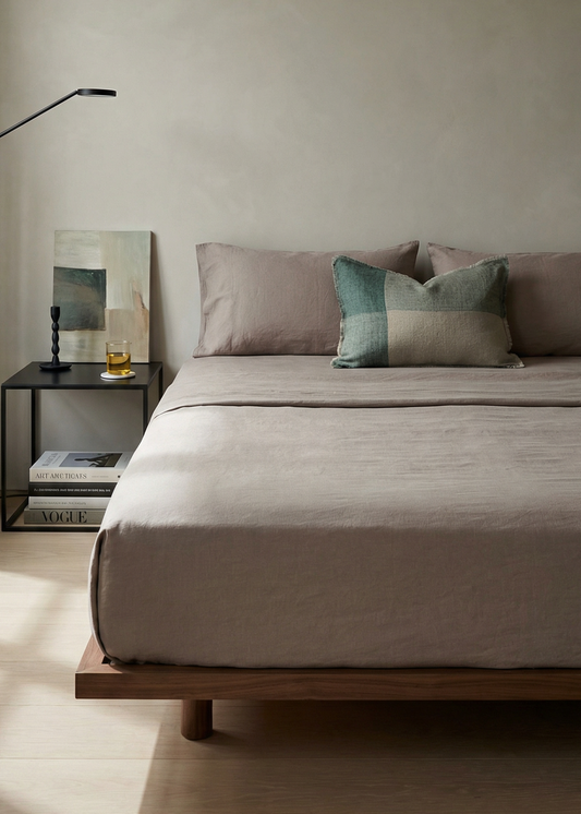 Minimalist bedroom with a bed, side table, and lamp in a neutral color scheme.