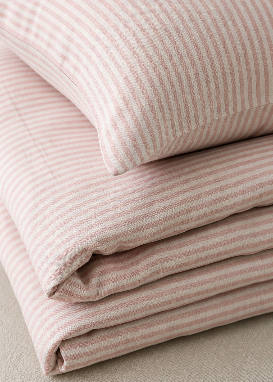 Stack of pink striped fabric on a neutral background