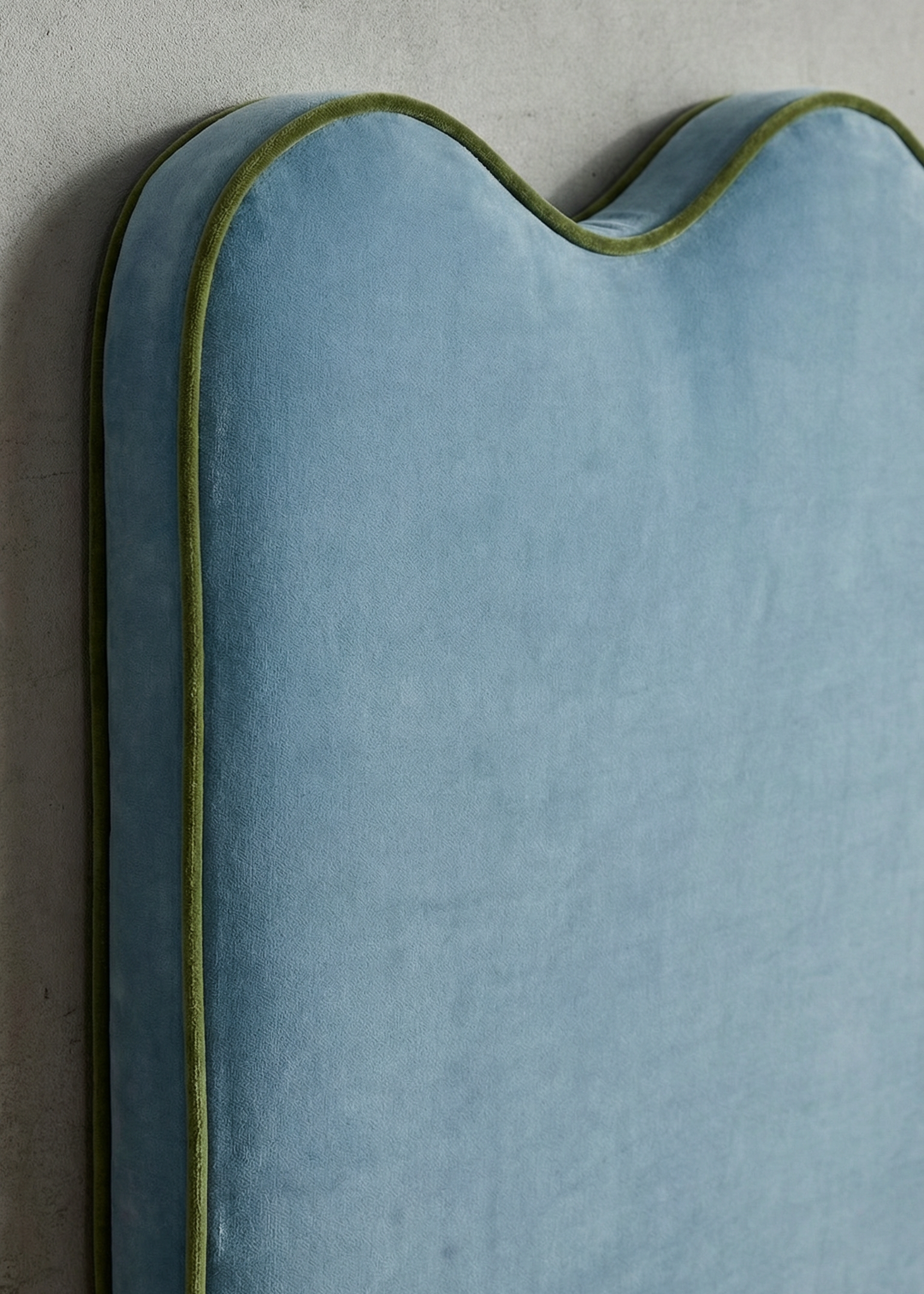 Blue cushion with green piping on a gray background