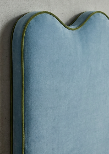 Blue cushion with green piping on a gray background