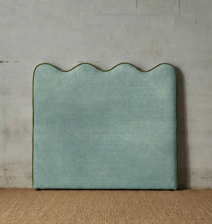 Green textured headboard against a neutral wall