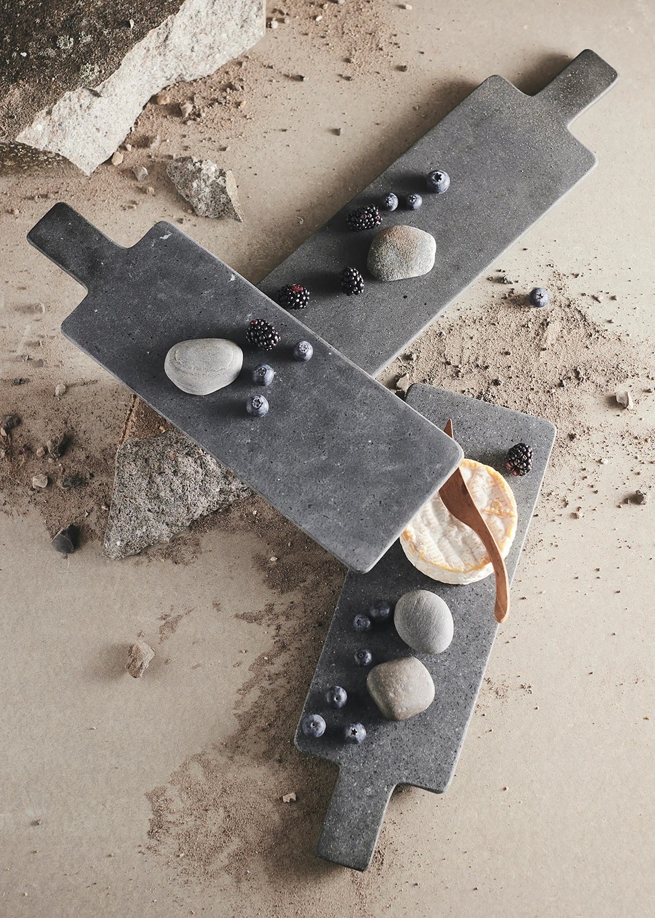 Two stone cutting boards with various stones and a bowl on a textured surface