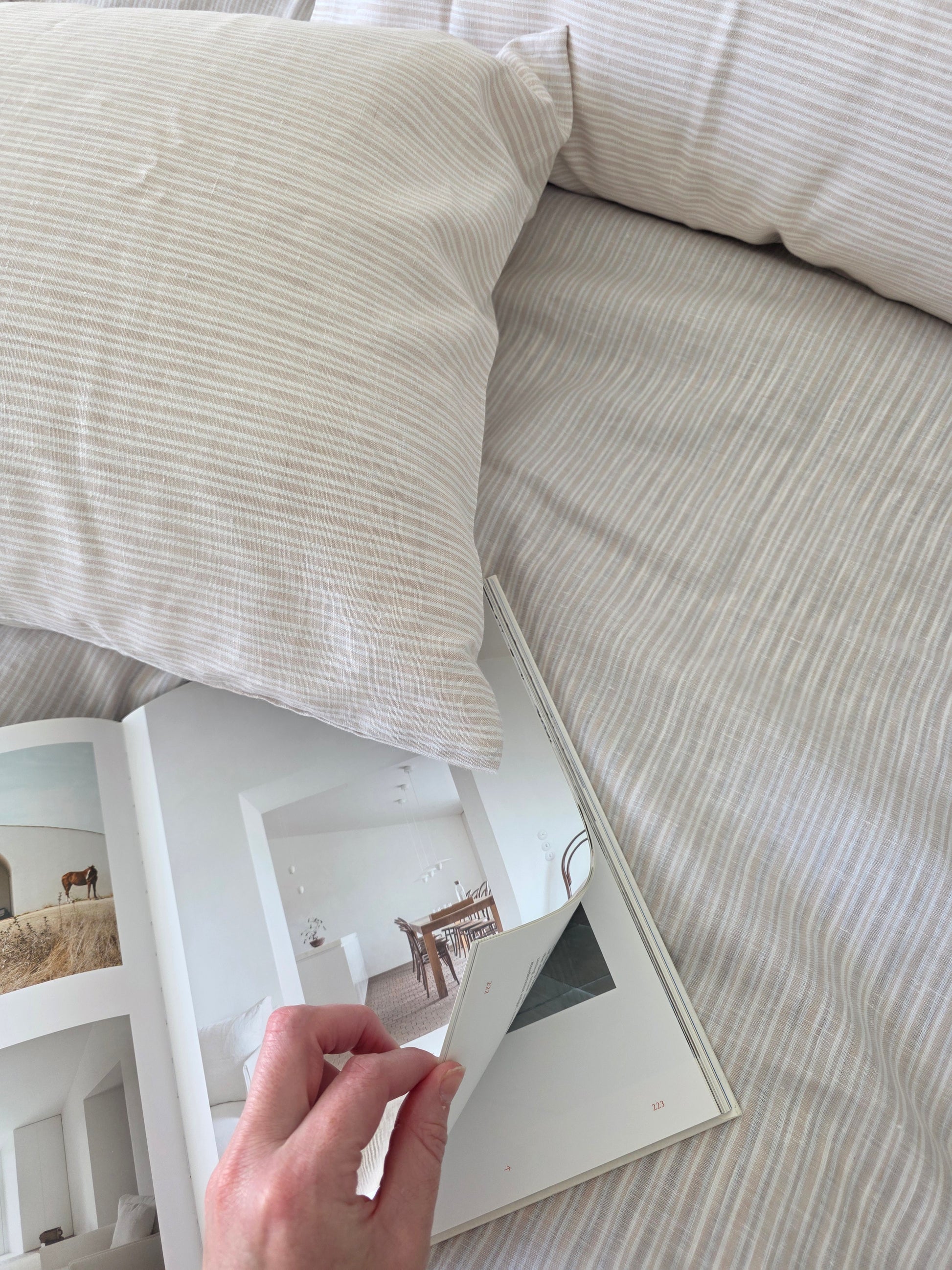 Person holding a small mirror next to a pillow on a textured surface