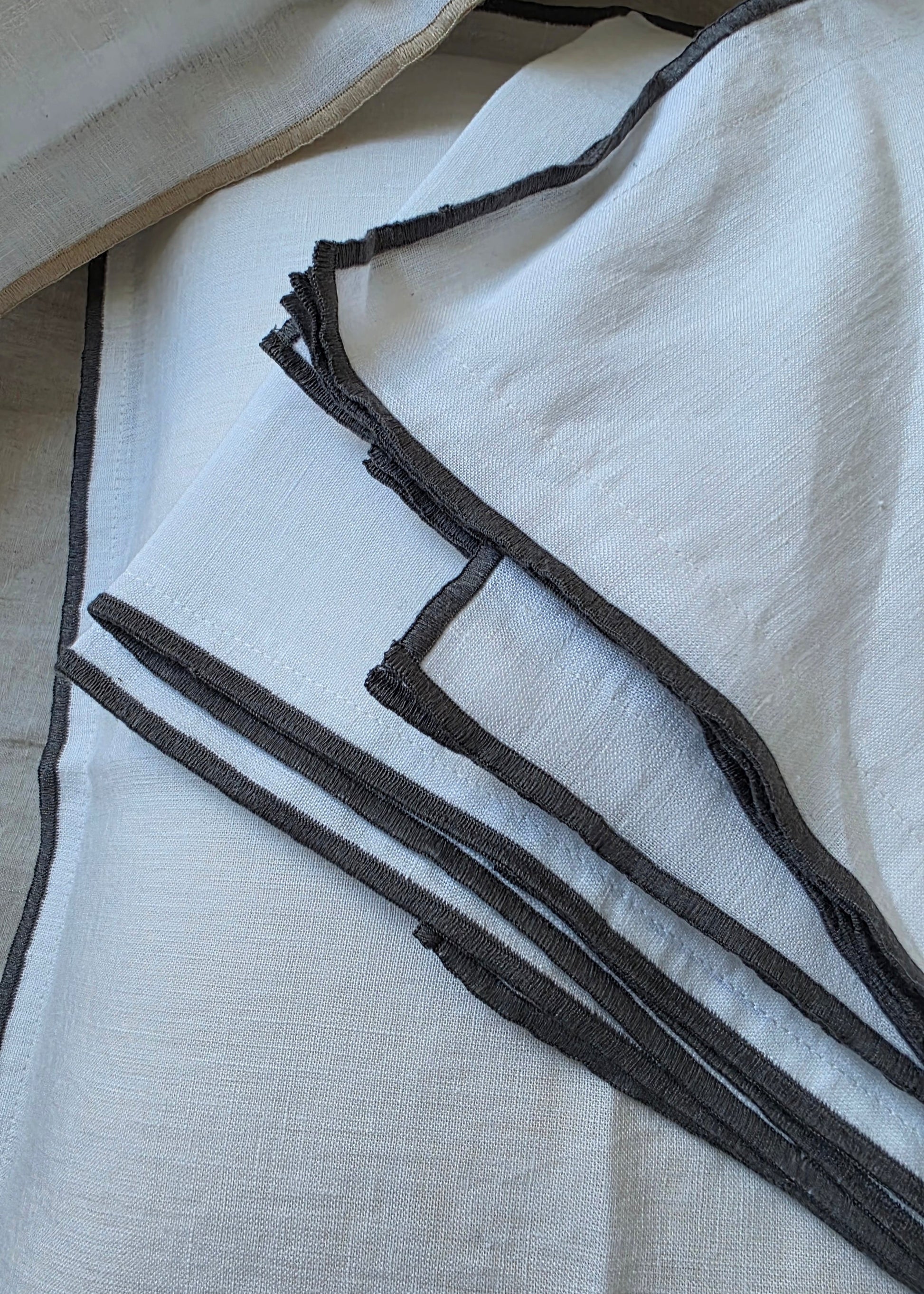 Close-up of a white fabric with black trim on a light gray background