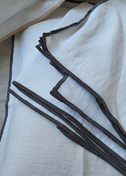 Close-up of a white fabric with black trim on a light gray background