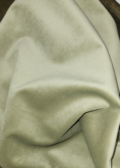 A close-up of draped fabric in a muted sage green color, showing its soft texture and folds.