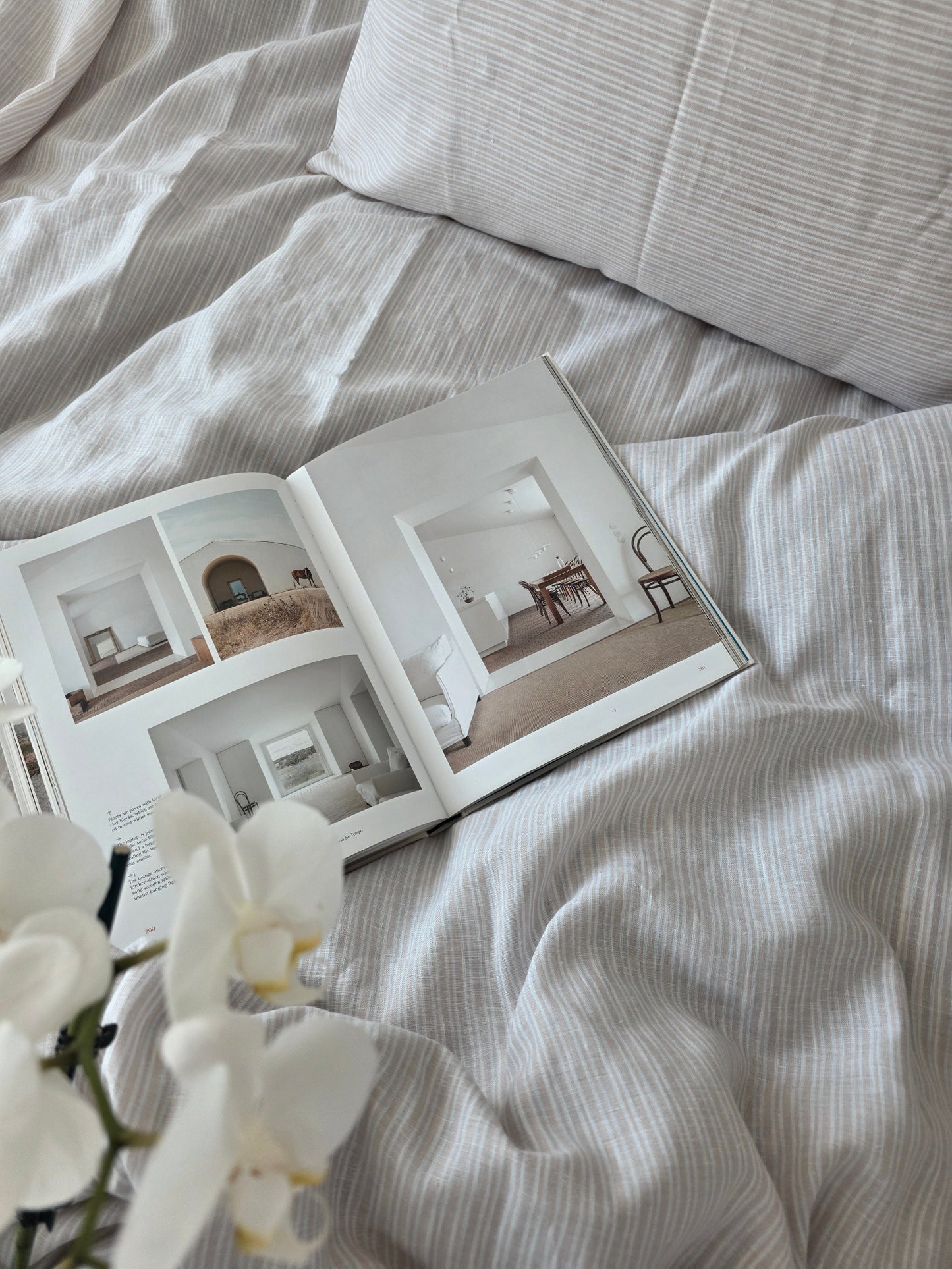 Open book on a bed with white orchids