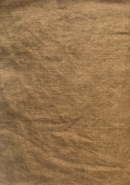 A square piece of textured tan fabric with frayed edges, laid flat on a white surface.