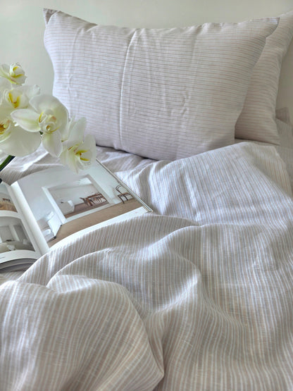 Neatly made bed with white bedding and a pillow, featuring a framed picture and white orchids.