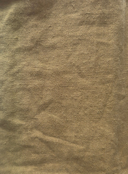 A square piece of textured tan or ochre-colored fabric laid flat on a white lined notebook page.