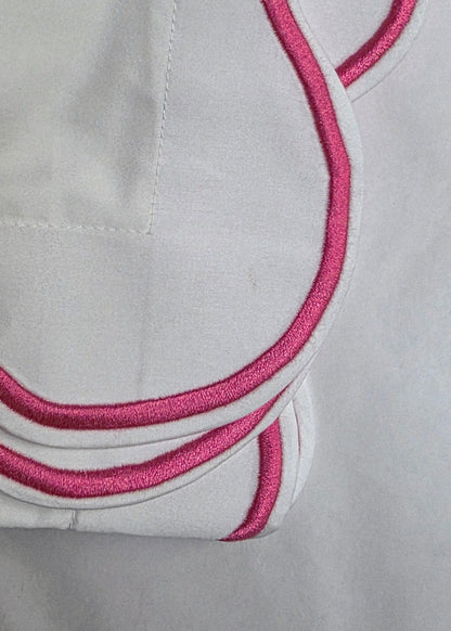 White fabric with pink embroidery on a light gray background
