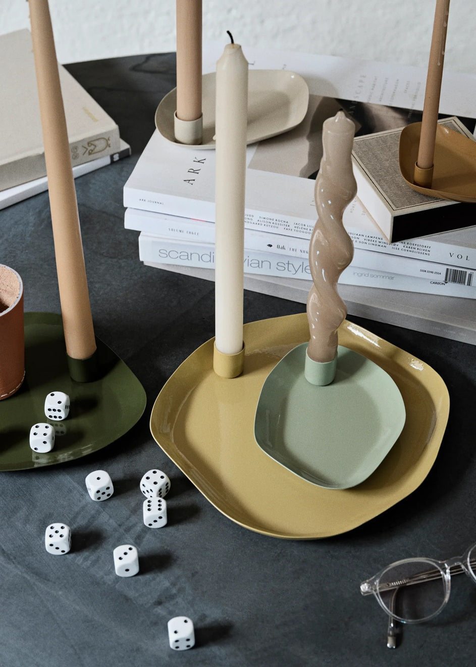 Decorative candle holders and plates on a dark surface with dice and glasses.