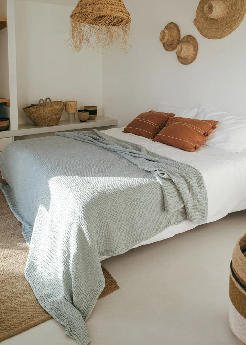 Bedroom with a bed, pillows, and decorative hats on the wall.