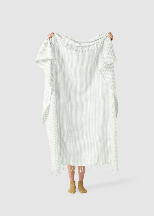 Person holding a white textured dress against a plain background