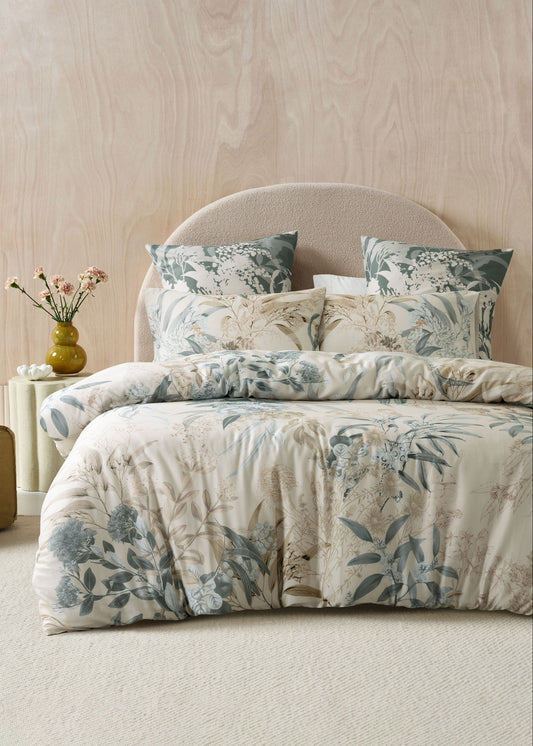 Floral bedding set on a bed in a bedroom with a wooden headboard.