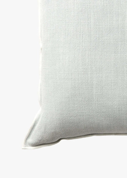 A square throw pillow in a light sage green linen fabric, shown against a plain white background.