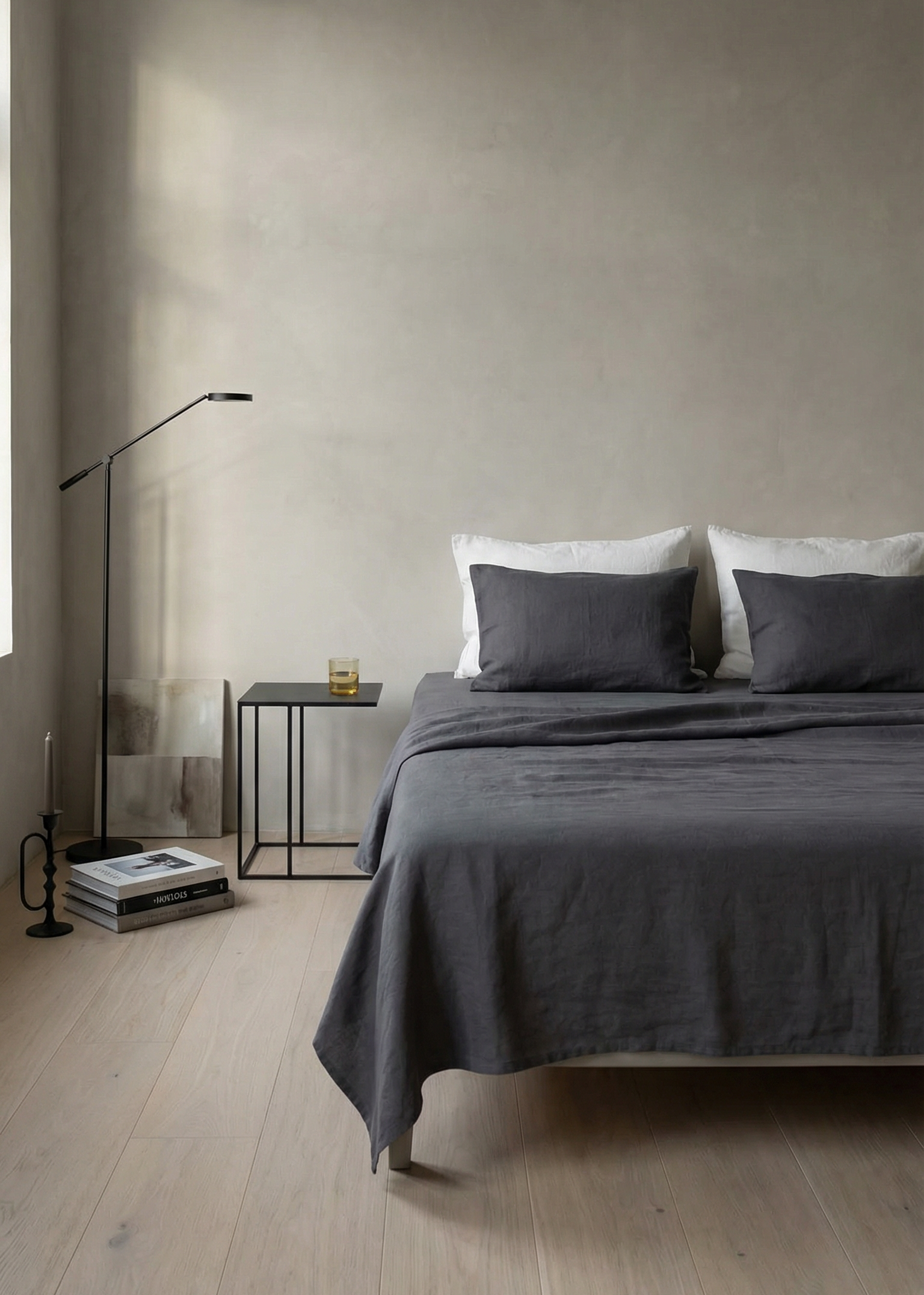 Minimalist bedroom with a bed, nightstand, and lamp against a plain wall.