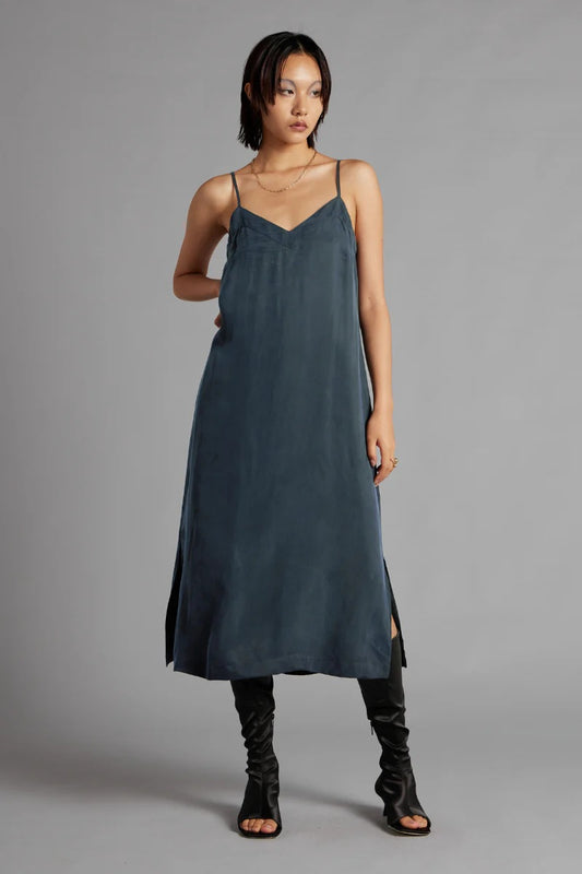 Woman wearing a dark blue slip dress against a gray background