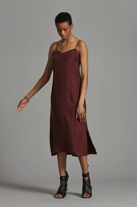 Woman wearing a burgundy slip dress against a gray background