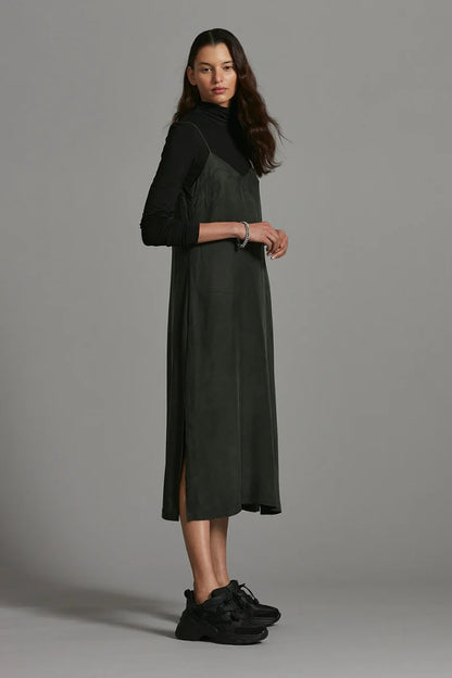Woman wearing a dark green dress with a high collar against a gray background