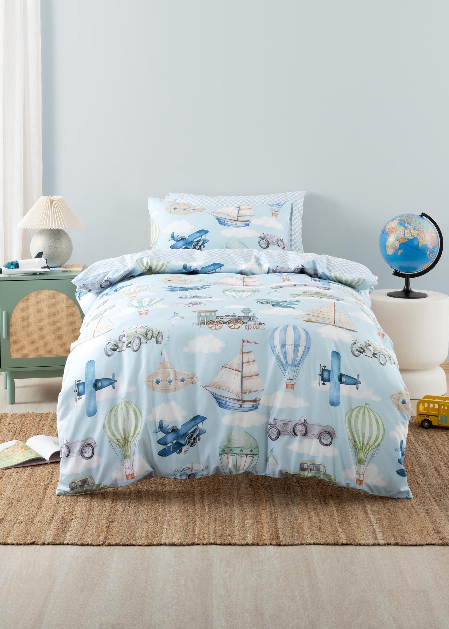 Children's bed with airplane, boat, and hot air balloon pattern in a room setting.