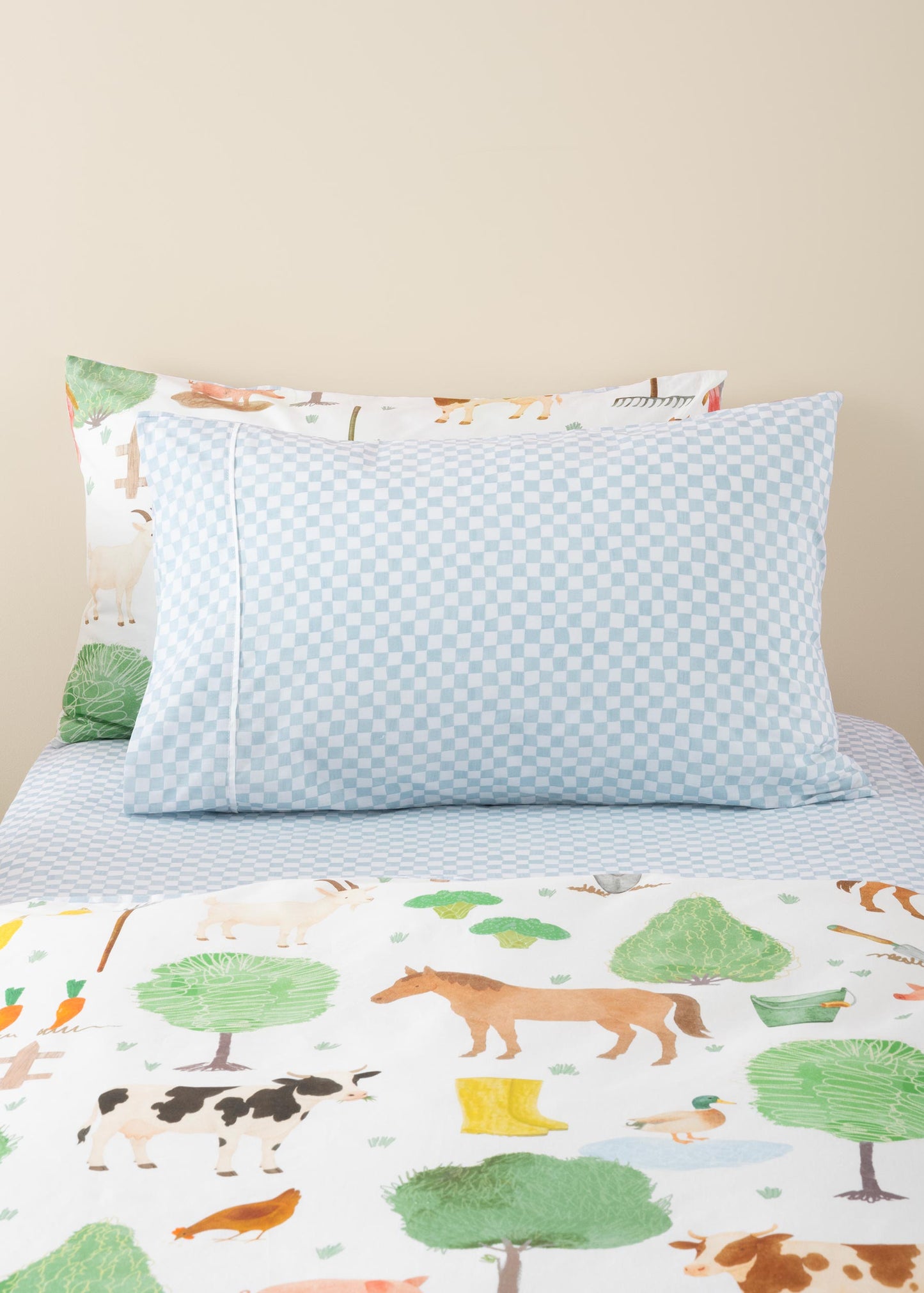 Children's bed with forest-themed bedding and pillows on a beige background