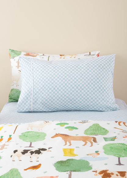 Children's bed with forest-themed bedding and pillows on a beige background