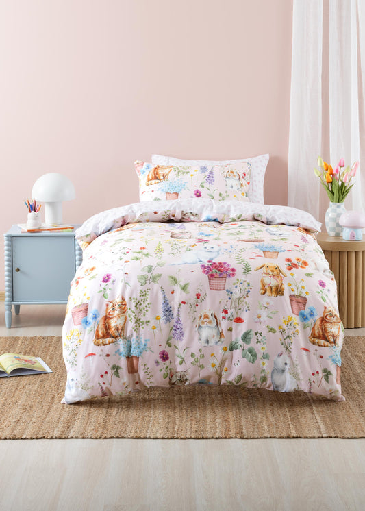 Floral and animal patterned comforter set on a bed in a bedroom with a pink wall.