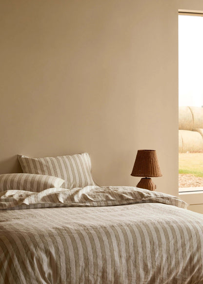 Bedroom with striped bedding and a lamp near a window with a view of farmland.