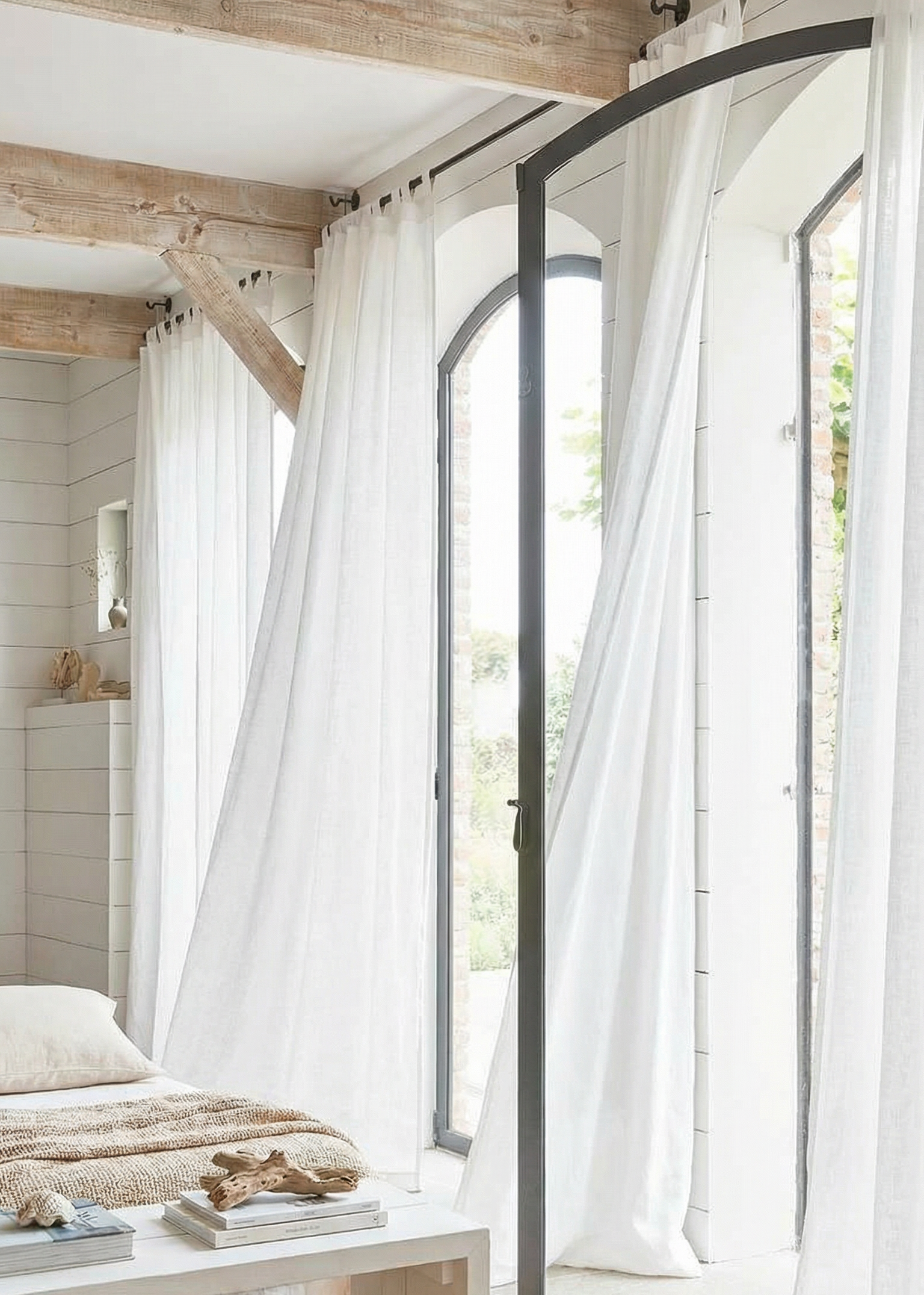 Modern bedroom with large windows, white curtains, and a wooden bed.