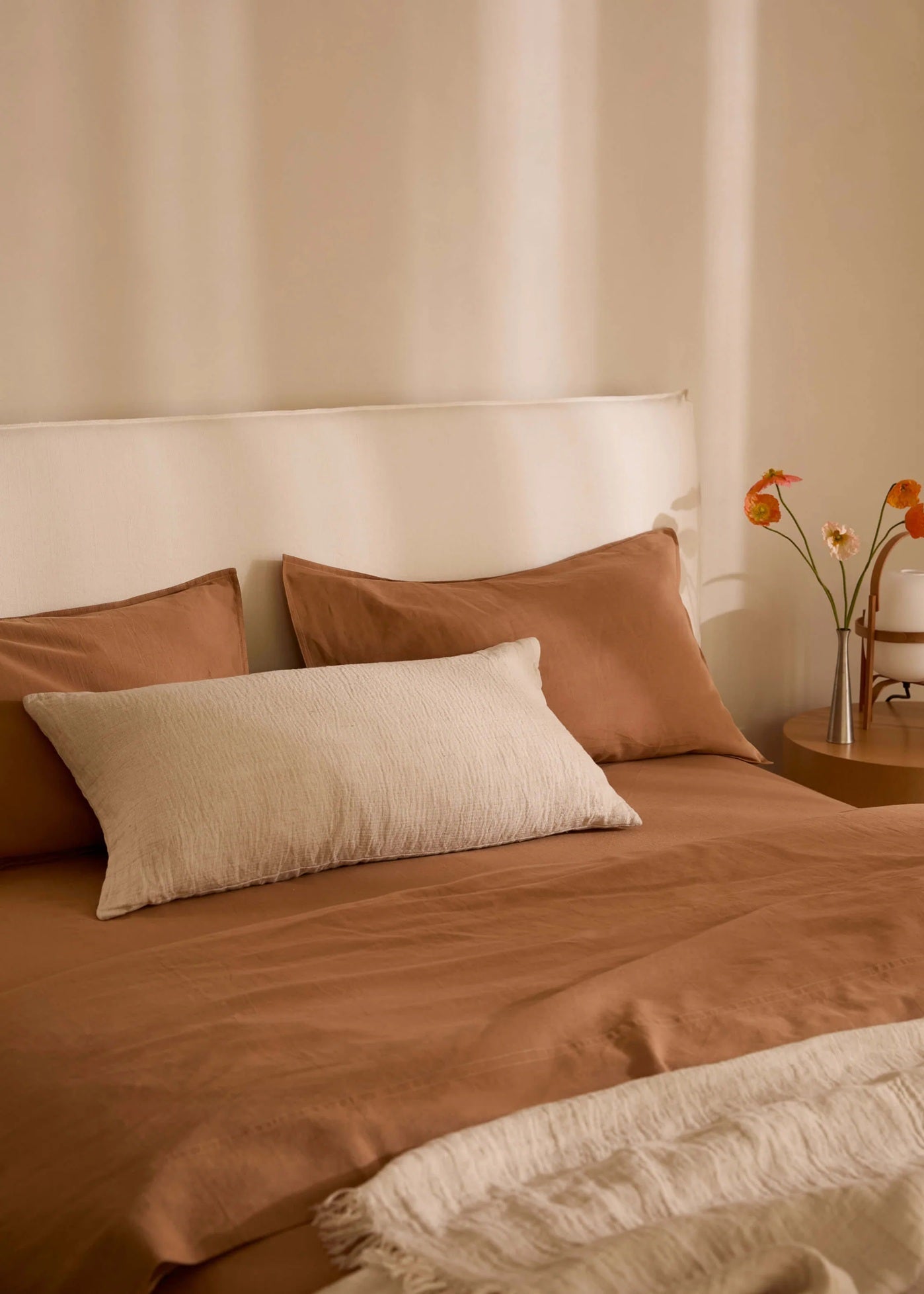 Bed with brown bedding and pillows in a softly lit room.