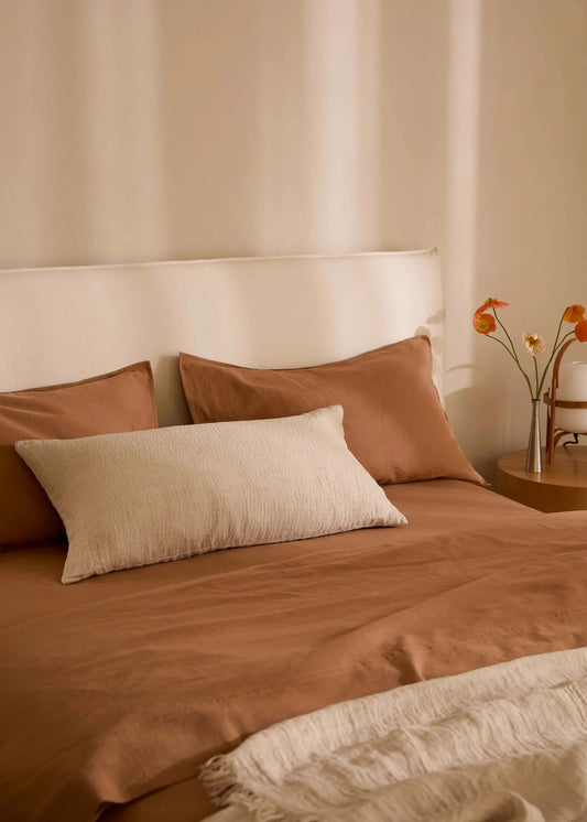 Bed with brown bedding and pillows in a softly lit room.