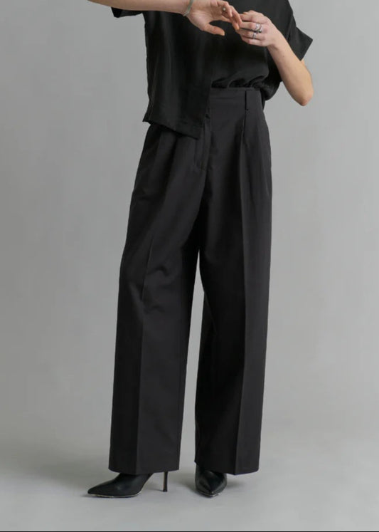Person wearing a black outfit against a gray background