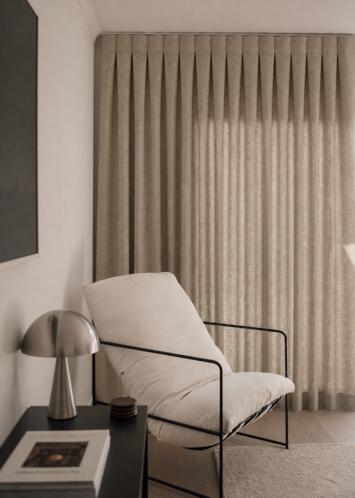 Modern interior with a white chair, side table, and curtain.