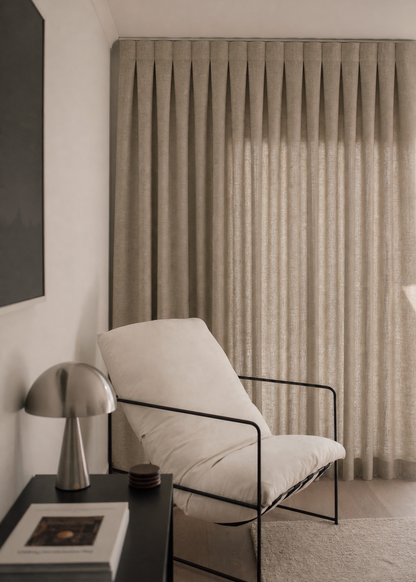 Modern interior with a white chair, side table, and curtain.