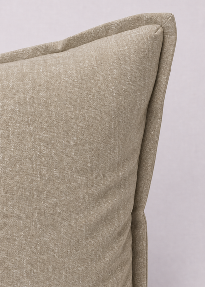 A close-up of a textured linen throw pillow in a light beige color, showing the corner seam and fabric weave against a neutral light gray background.