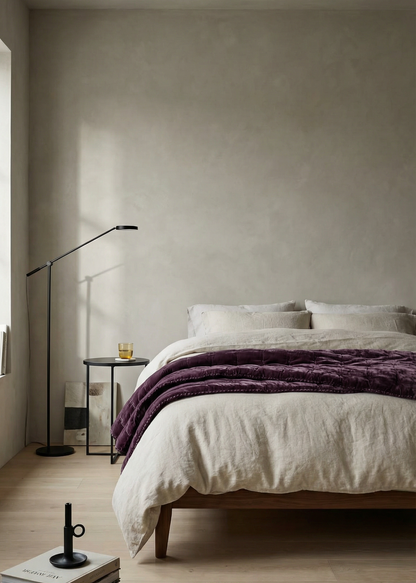 Modern bedroom with a bed, lamp, and decor items on a neutral background