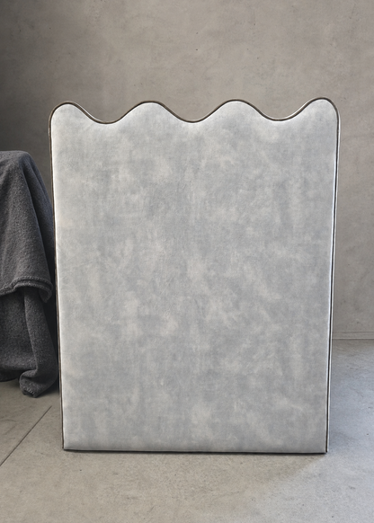 Gray upholstered headboard against a plain wall
