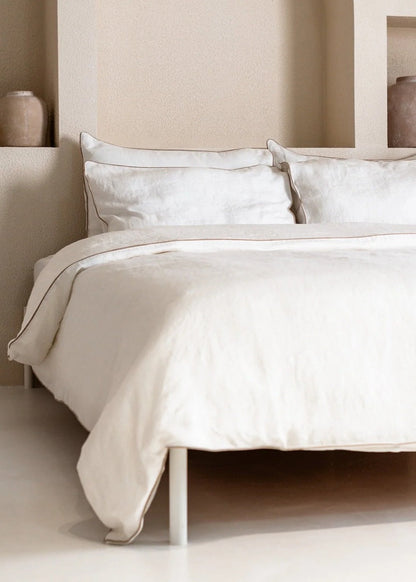 Neatly made bed with white bedding in a minimalistic bedroom setting.