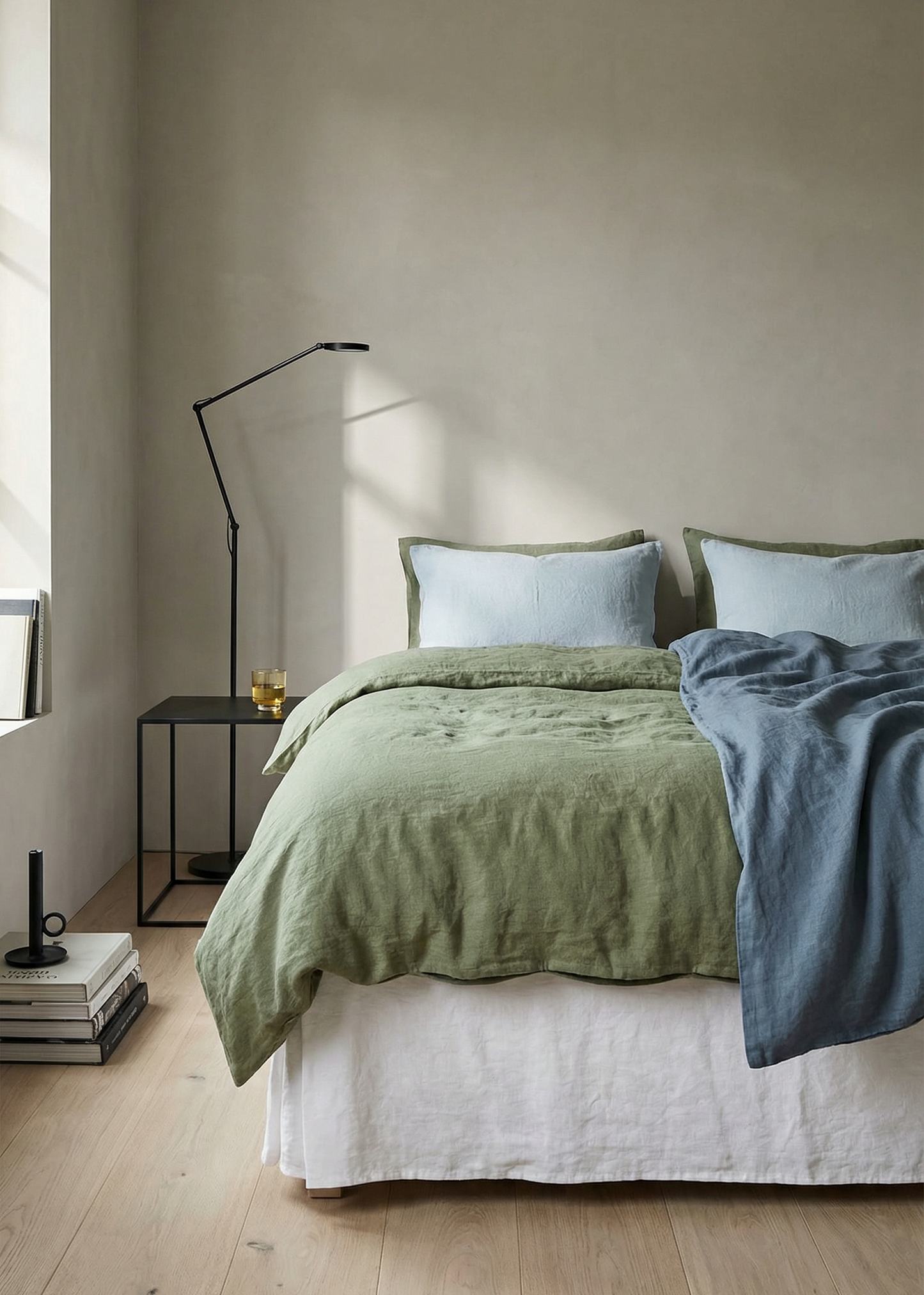 Bedroom with green and blue bedding on a bed against a neutral wall.