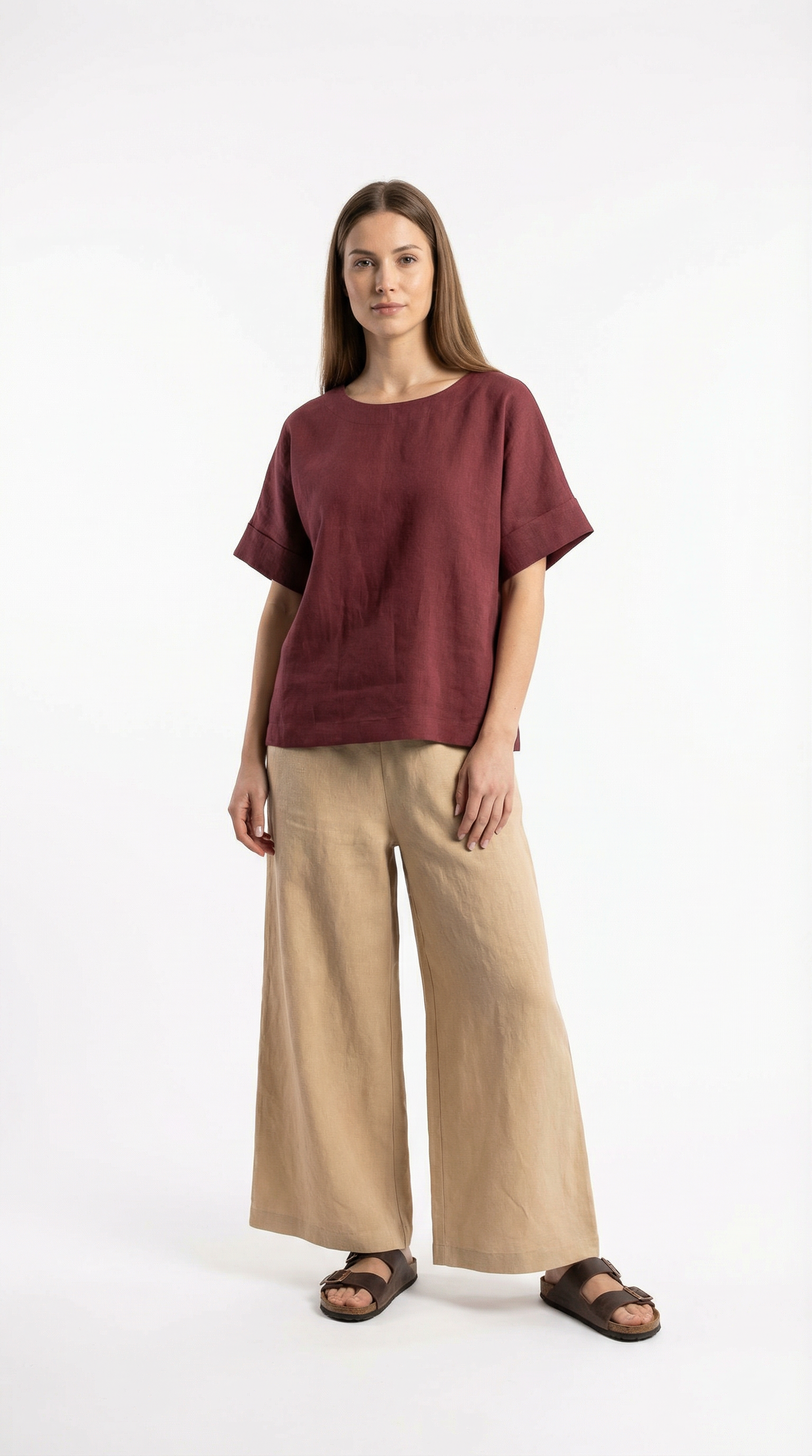 Woman wearing a burgundy top and beige pants on a white background