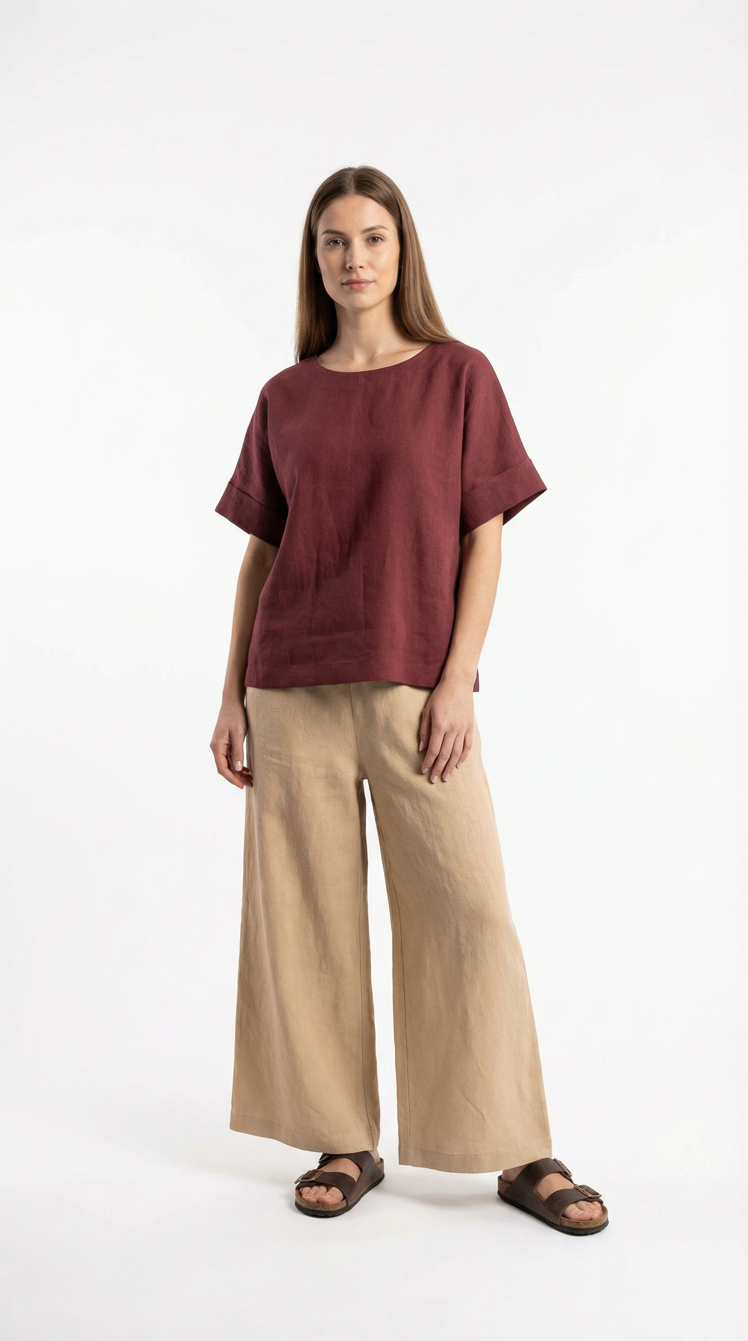 Woman wearing a burgundy top and beige pants on a white background