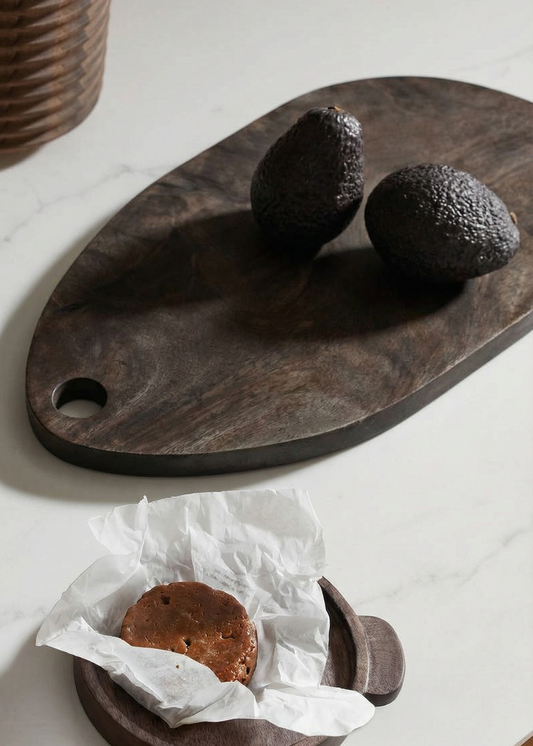 Wooden cutting board with avocados and a piece of paper on a white surface